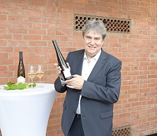 Ratskellermeister Karl-Josef Krötz steht neben einem Stehtisch und hält eine Flasche Senatswein in den Händen