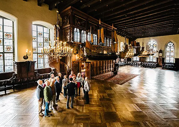 Führung in der oberen Rathaushalle. Personengruppe schut sich den Raum an.