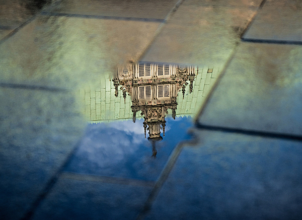 Spiegelung des Rathauses in einer Pfütze.
