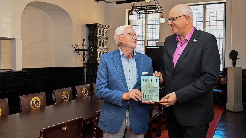 Prof. Gerold Wefer (links) übergibt Bürgermeister Andreas Bovenschulte in der Wittheitsstube des Rathauses die Dokumentation zum 100-jährigen Bestehen der Wittheit zu Bremen.
