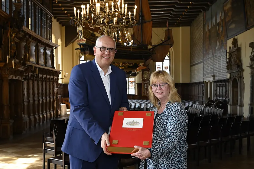 Rathaus-Mitarbeiterin Michaela Lohaus übergibt das neue Goldene Buch an Bürgermeister Andreas Bovenschulte.