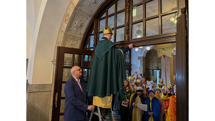 Der Bürgermeister hält die Leiter, der Sternsinger schreibt: 20*C+M+B+26 steht seit heute über dem Eingang zum Rathaus.